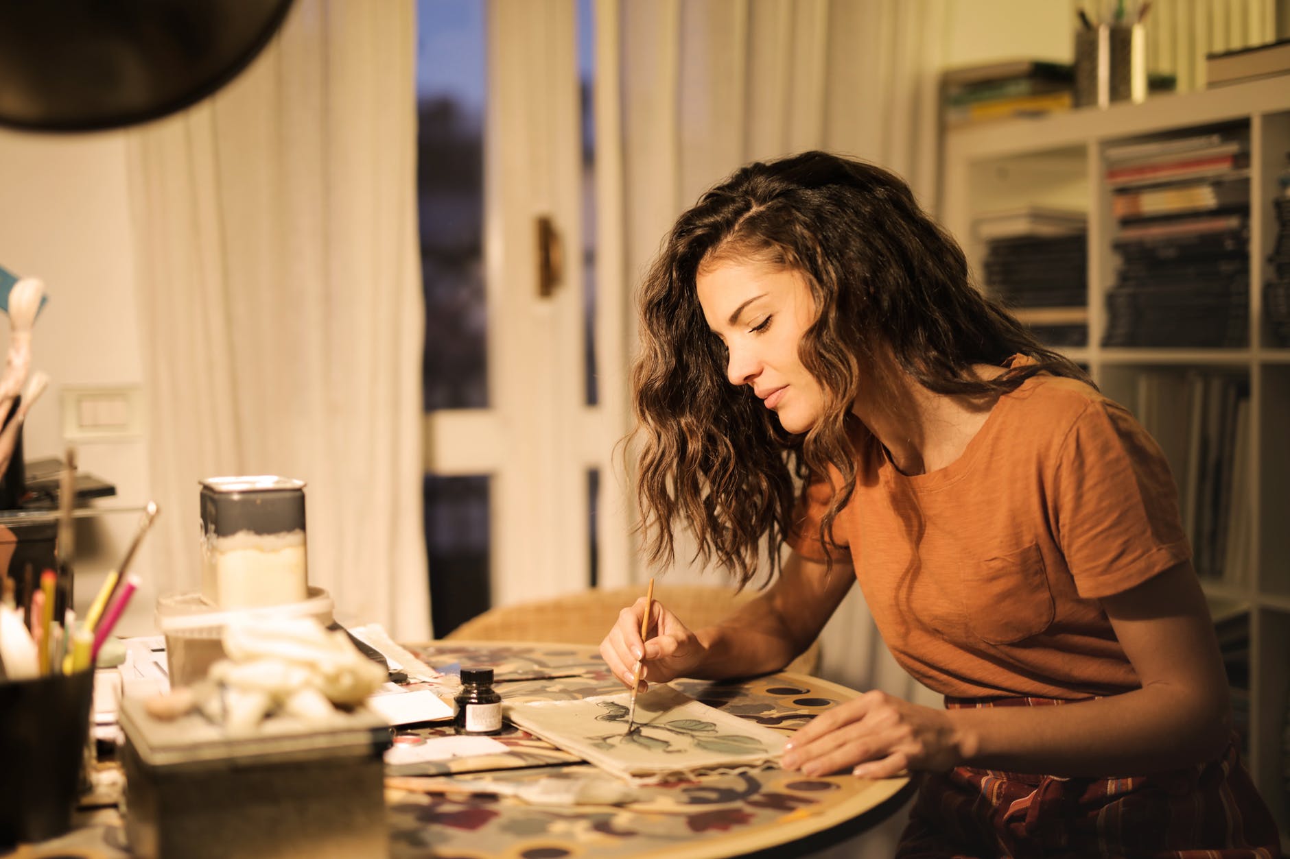 young woman painting on paper at workplace